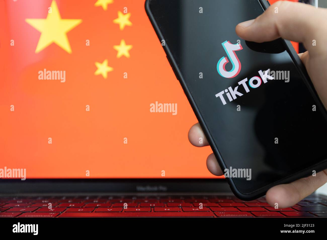 TikTok-App auf dem Smartphone und China-Flagge im Hintergrund. Stockfoto