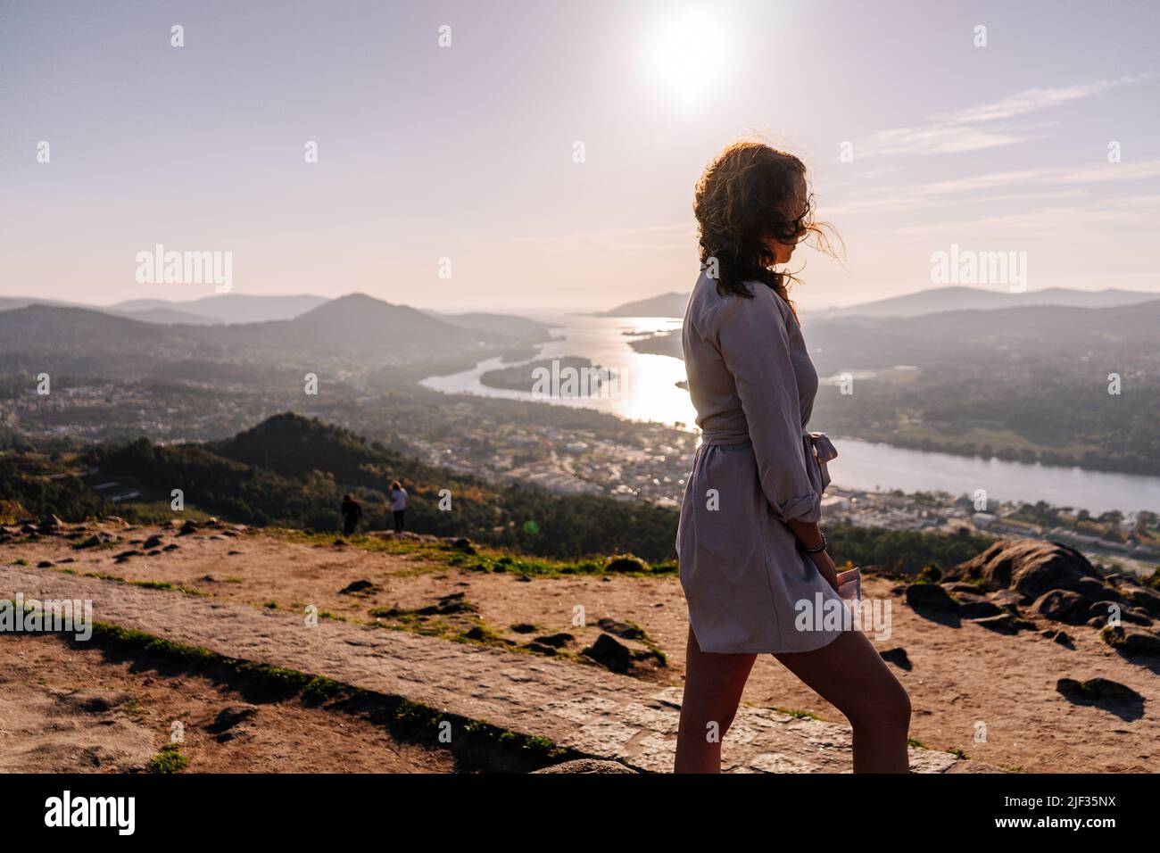Junge Frau auf einem Berg gegen eine Landschaft mit einem Fluss und Bergen Stockfoto