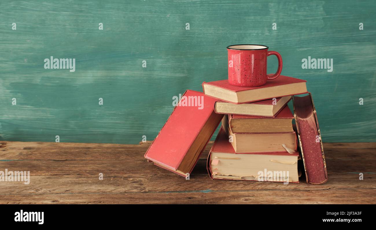 Offenes Buch, altes Hardback-Buch und eine Tasse Kaffee auf grünem Hintergrund. Bildung, Lesen, Forschungskonzept. Stockfoto
