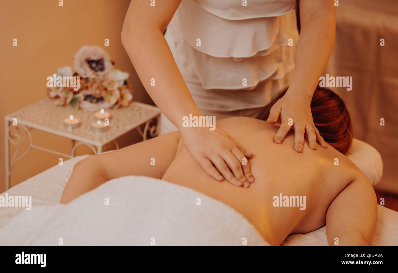 Draufsicht auf glücklichen Masseur, der junge Frau auf einen Massageliege massiert, Konzept der Massage-Spa-Behandlungen, gesunder Lebensstil Stockfoto