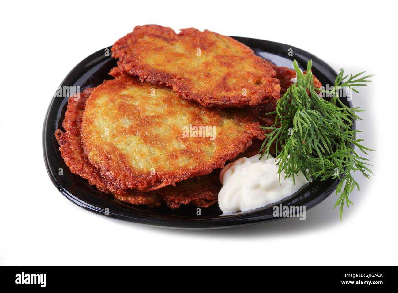 Kartoffelpfannkuchen mit Sauerrahm und Dill auf einem schwarzen Porzellanteller Stockfoto