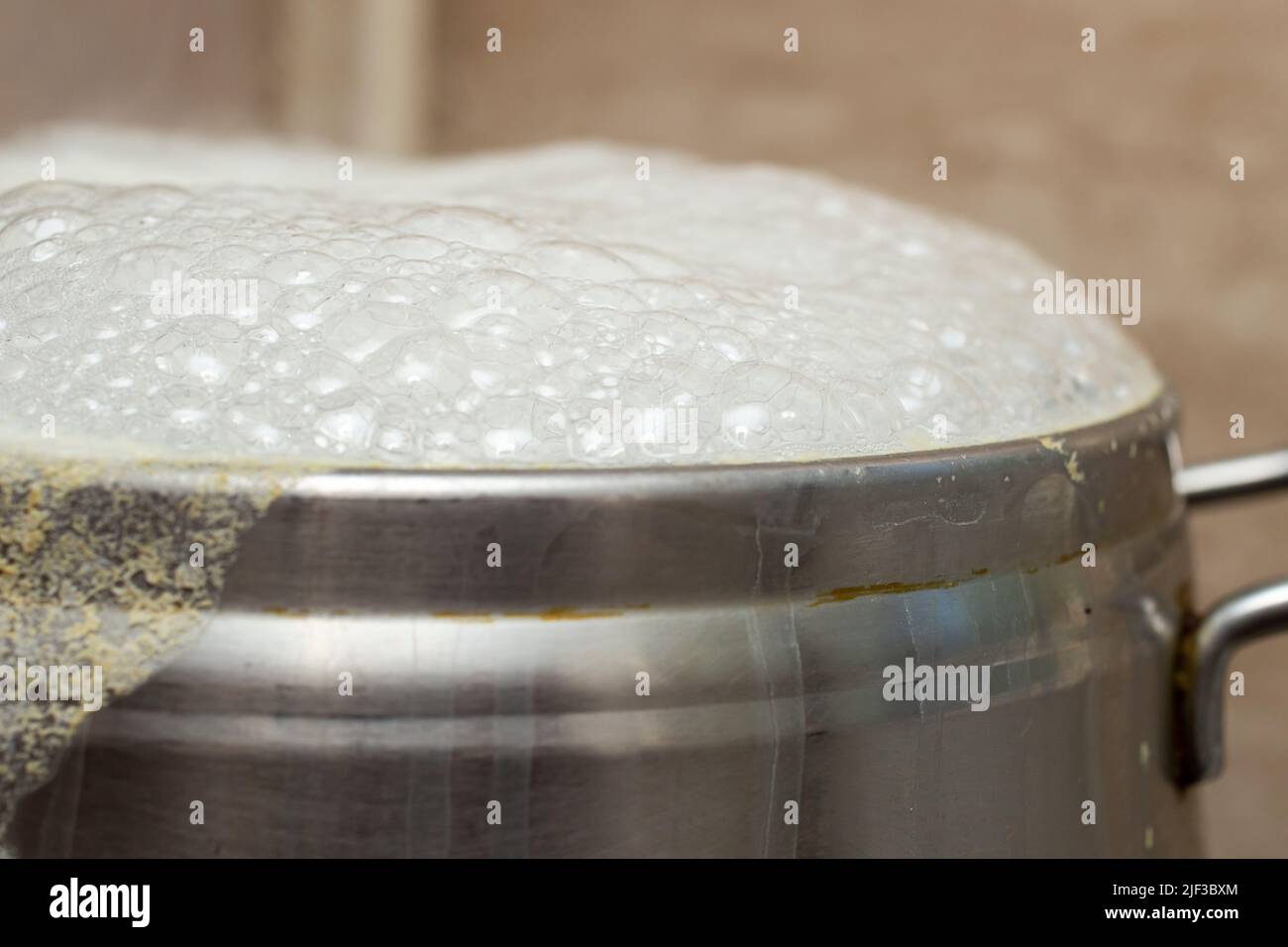 Silberner Inox-Topf, der mit weißen Blasen überkocht, Nahaufnahme-Makro Stockfoto