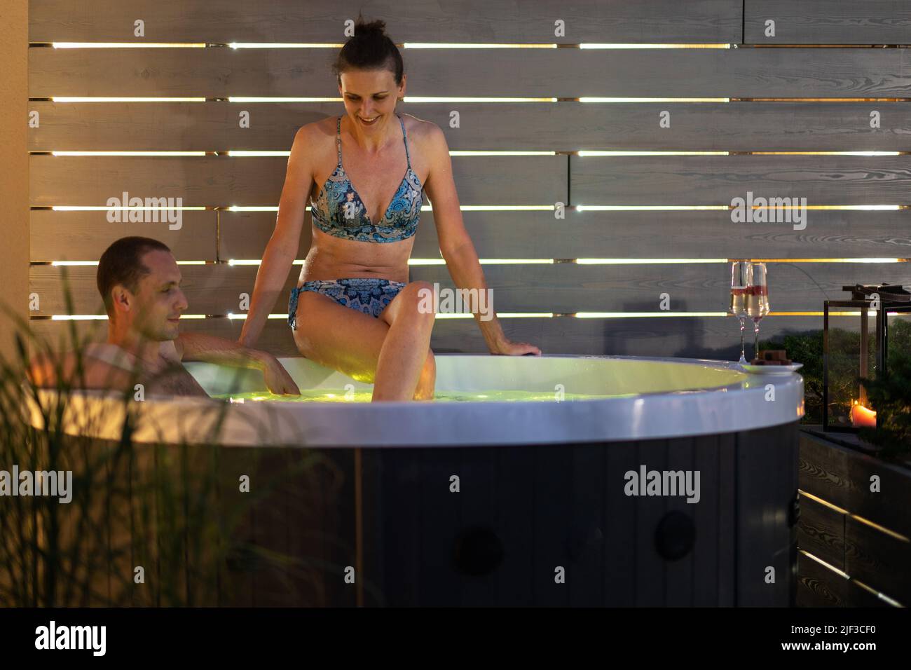 Kaukasisches Paar mit 40s Jahren, das während des warmen Sommerabends seine Freizeit in einem Hot Tub Garden Spa genießt. Entspannung und Wellness. Stockfoto