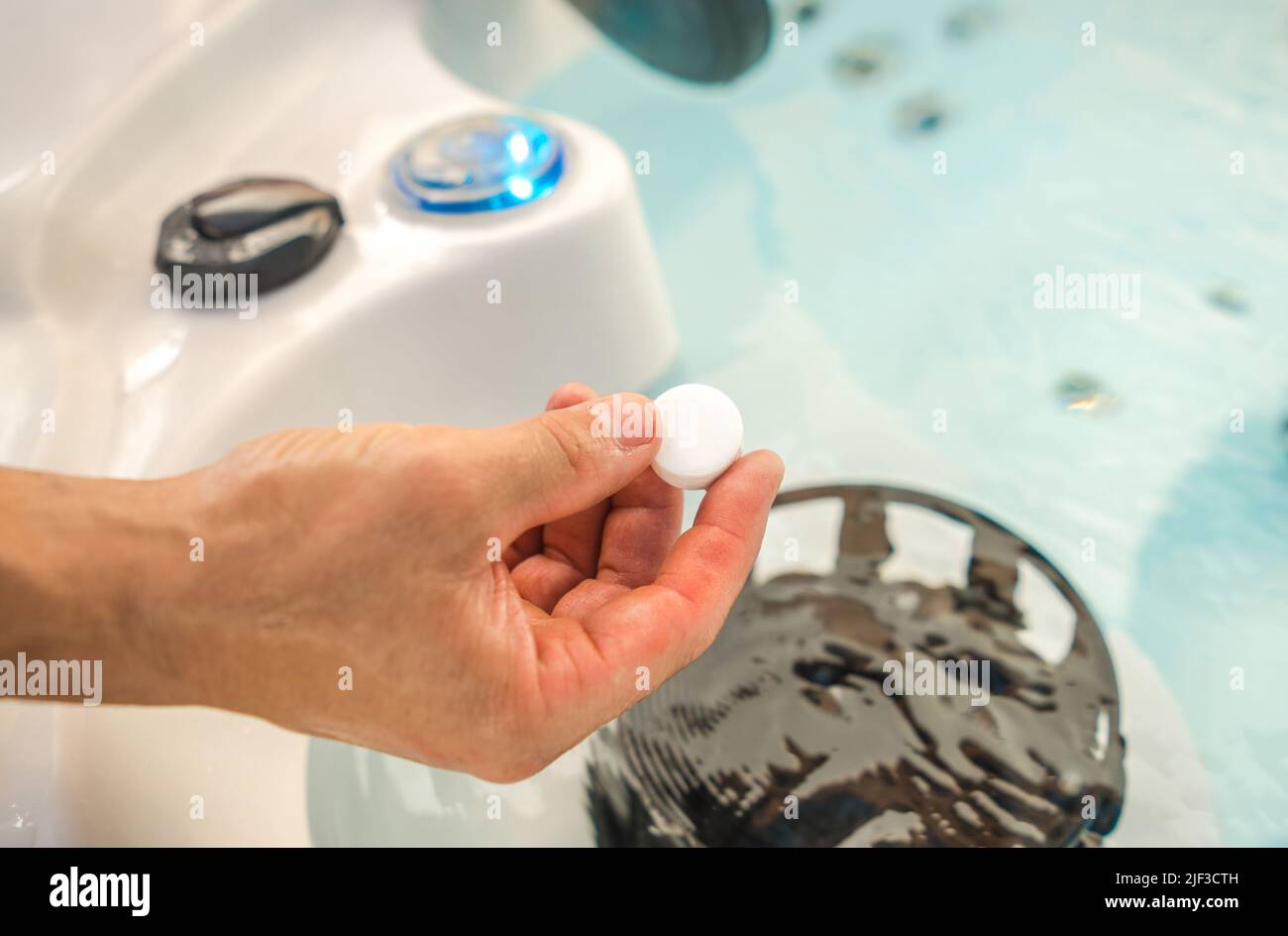 Kaukasische Männer verwenden Chlor-Tabs in einem Whirlpool-Spa, um gesundes und hochwertiges Wasser in der Badewanne zu erhalten. Stockfoto