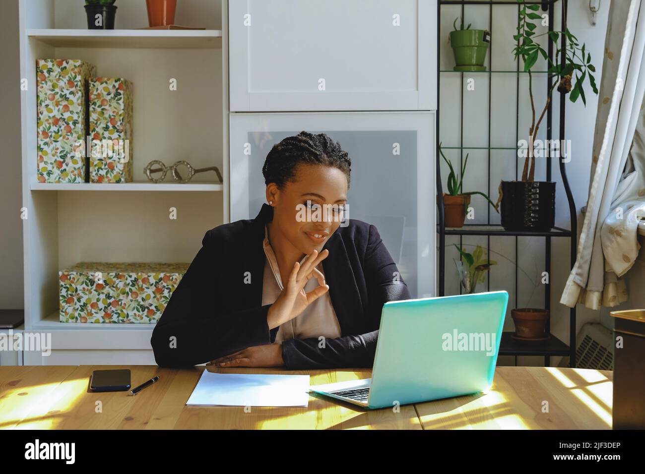 Lächelnd Junge Erwachsene Unternehmer freiberufliche schwarze Frau Kleinunternehmer auf Videoanruf zeigt ok Zeichen mit Laptop arbeiten im Home Office aufgenommen Stockfoto