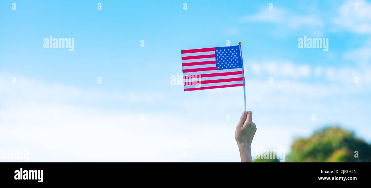 Hand hält die Flagge der Vereinigten Staaten von Amerika auf blauem Himmel Hintergrund. USA: Feiertag der Veteranen, Gedenkstätte, Unabhängigkeit (4. Juli) und Labor Day con Stockfoto