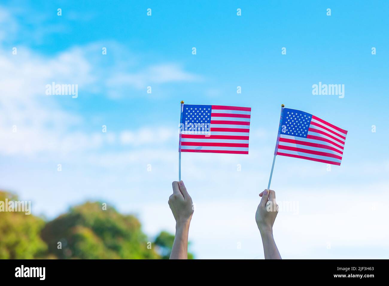 Hand hält die Flagge der Vereinigten Staaten von Amerika auf blauem Himmel Hintergrund. USA: Feiertag der Veteranen, Gedenkstätte, Unabhängigkeit (4. Juli) und Labor Day con Stockfoto