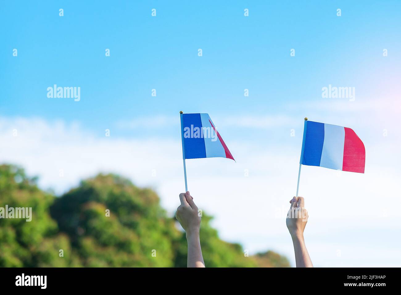 Hand hält Frankreich Flagge auf blauem Himmel Hintergrund. Feiertag des französischen Nationaltages, Bastille Tag und glückliche Feier Konzepte Stockfoto