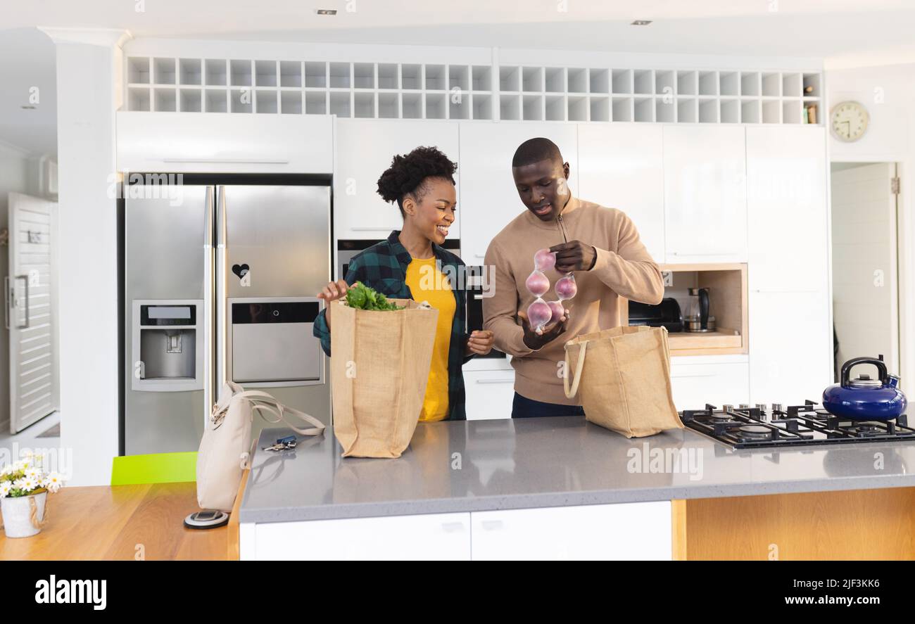 afroamerikanisches Ehepaar mit mittleren Erwachsenen, das Lebensmittel aus der Tasche auf der Kücheninsel auspacken konnte Stockfoto