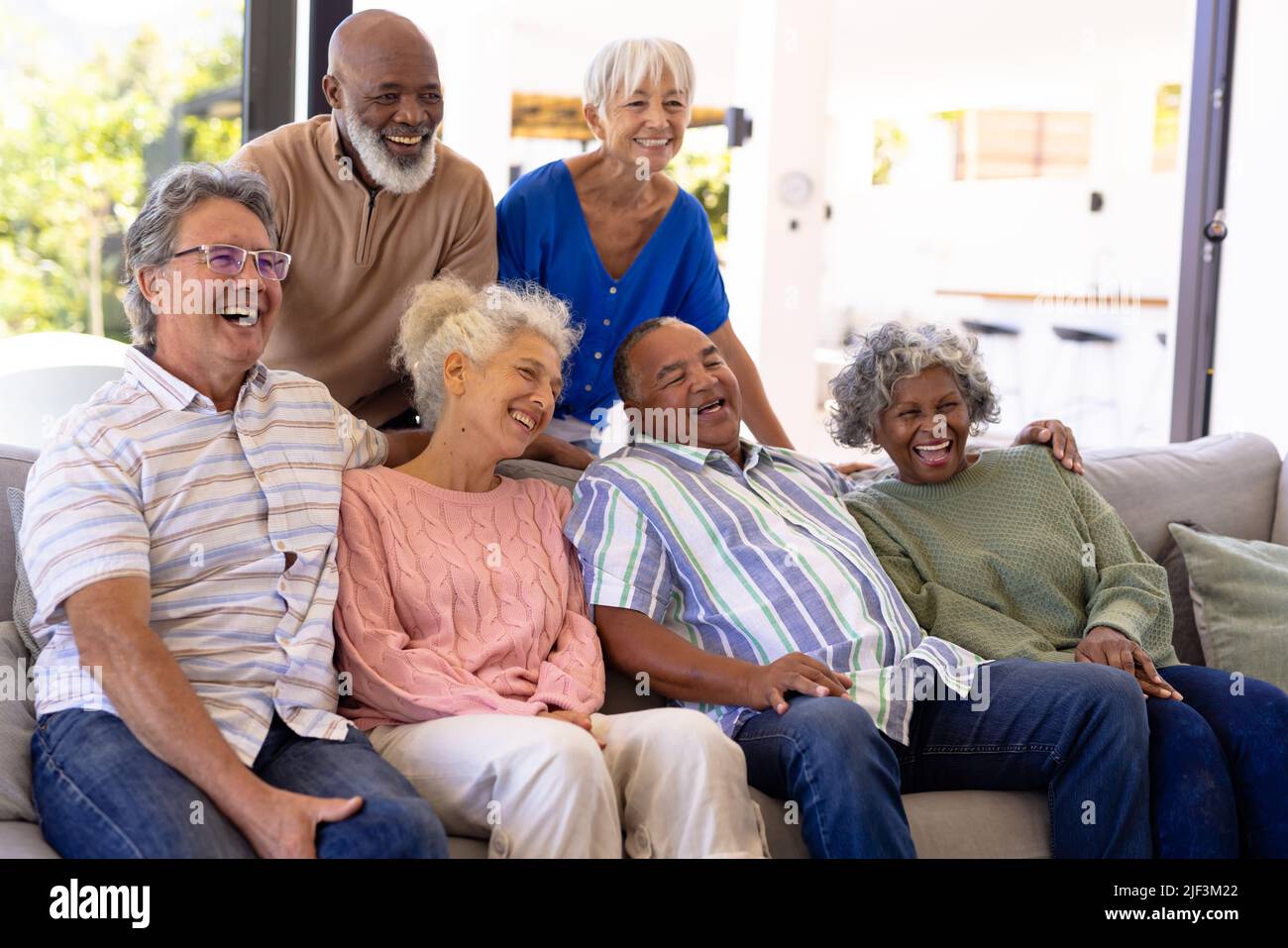 Fröhliche multirassische männliche und weibliche ältere Freunde, die lachen, während sie sich im Pflegeheim entspannen Stockfoto