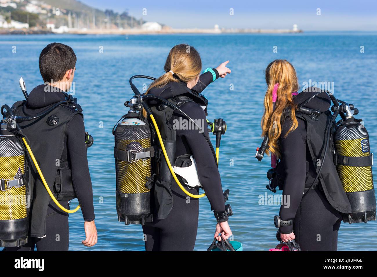 Taucher, die am Strand trainieren und ihren Tauchgang planen, weisen auf das Meer hin, das ihr komplettes Tauchkit trägt Stockfoto