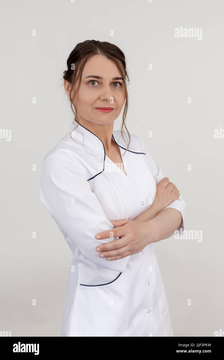 Vertikale selbstbewusste weibliche Ärztin in weißem Stativ, Look Kamera im Studio. Physiotherapeut, Sanitäter, Orthopäde Stockfoto