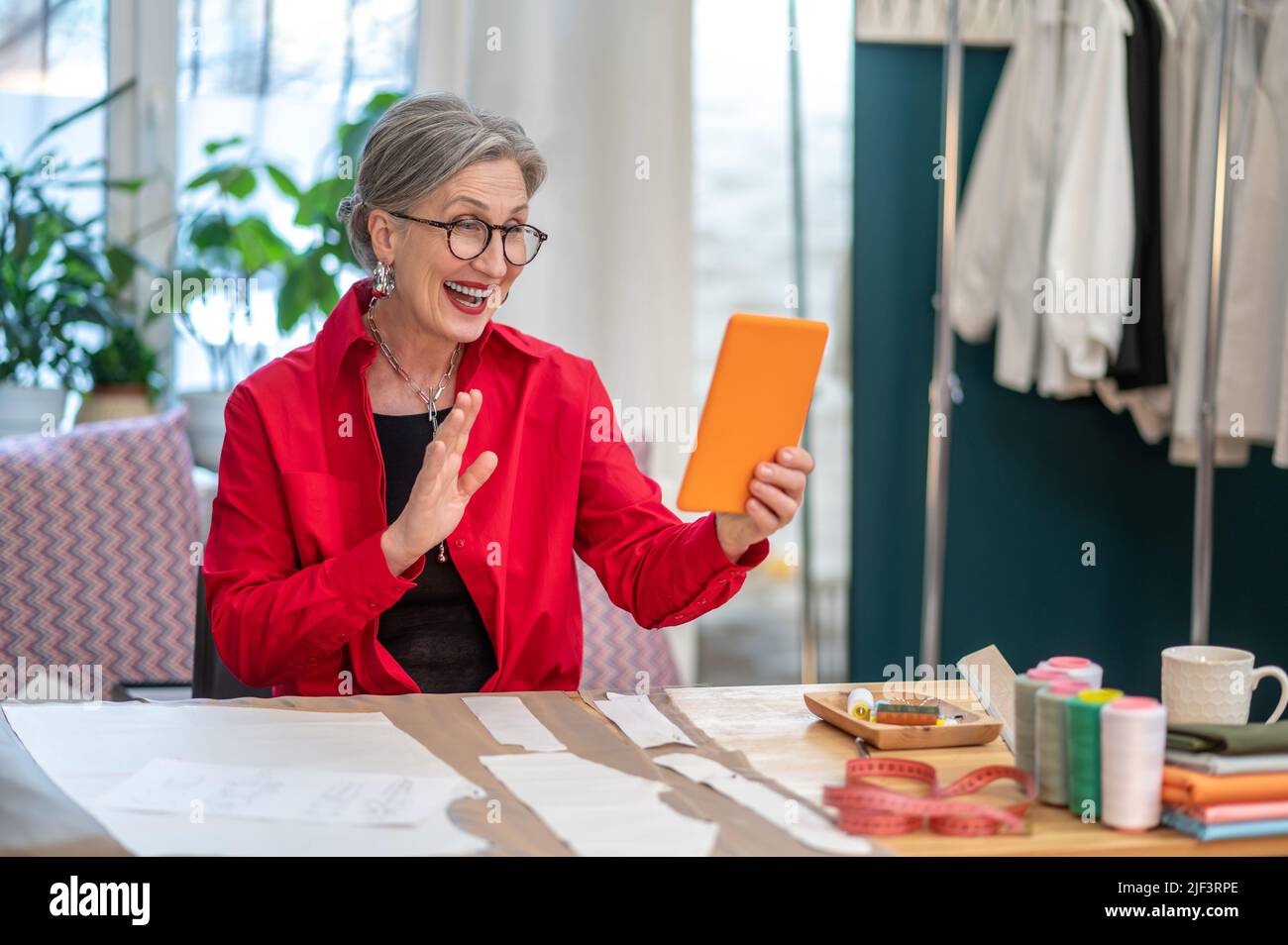 Frau gestikuliert Gruß Blick auf Smartphone Stockfoto