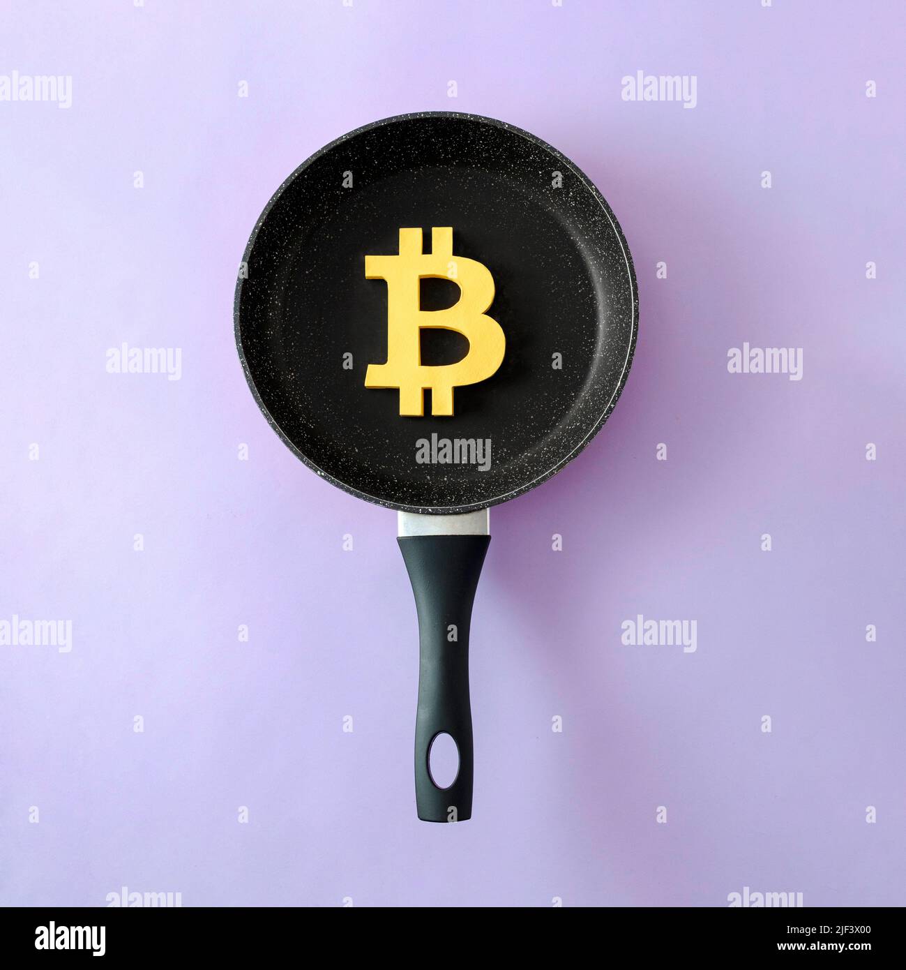 Das Symbol der modernen digitalen Kryptowährung Bitcoin in einer Pfanne als Konzept von Risiko, Rezession und anderen finanziellen Problemen. Stockfoto