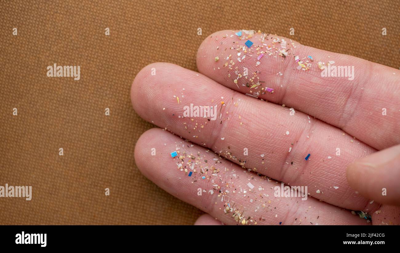 Mikroplastikpartikel auf einem menschlichen Finger für Kalk. Konzept für Wasserverschmutzung und globale Erwärmung. Stockfoto