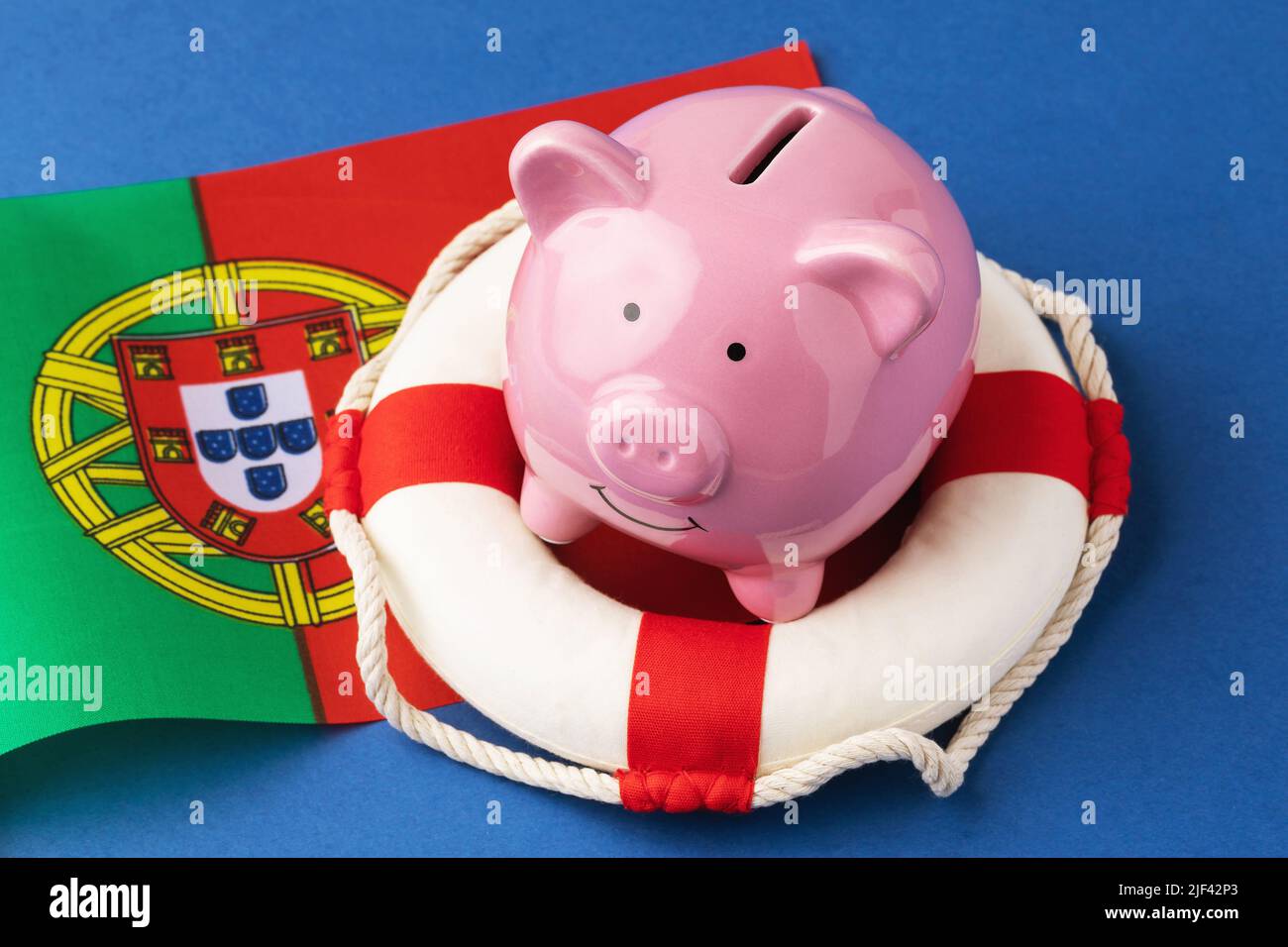 Sparschwein, Rettungsring und Flagge auf blauem Hintergrund, das Konzept der Rettung der portugiesischen Wirtschaft Stockfoto