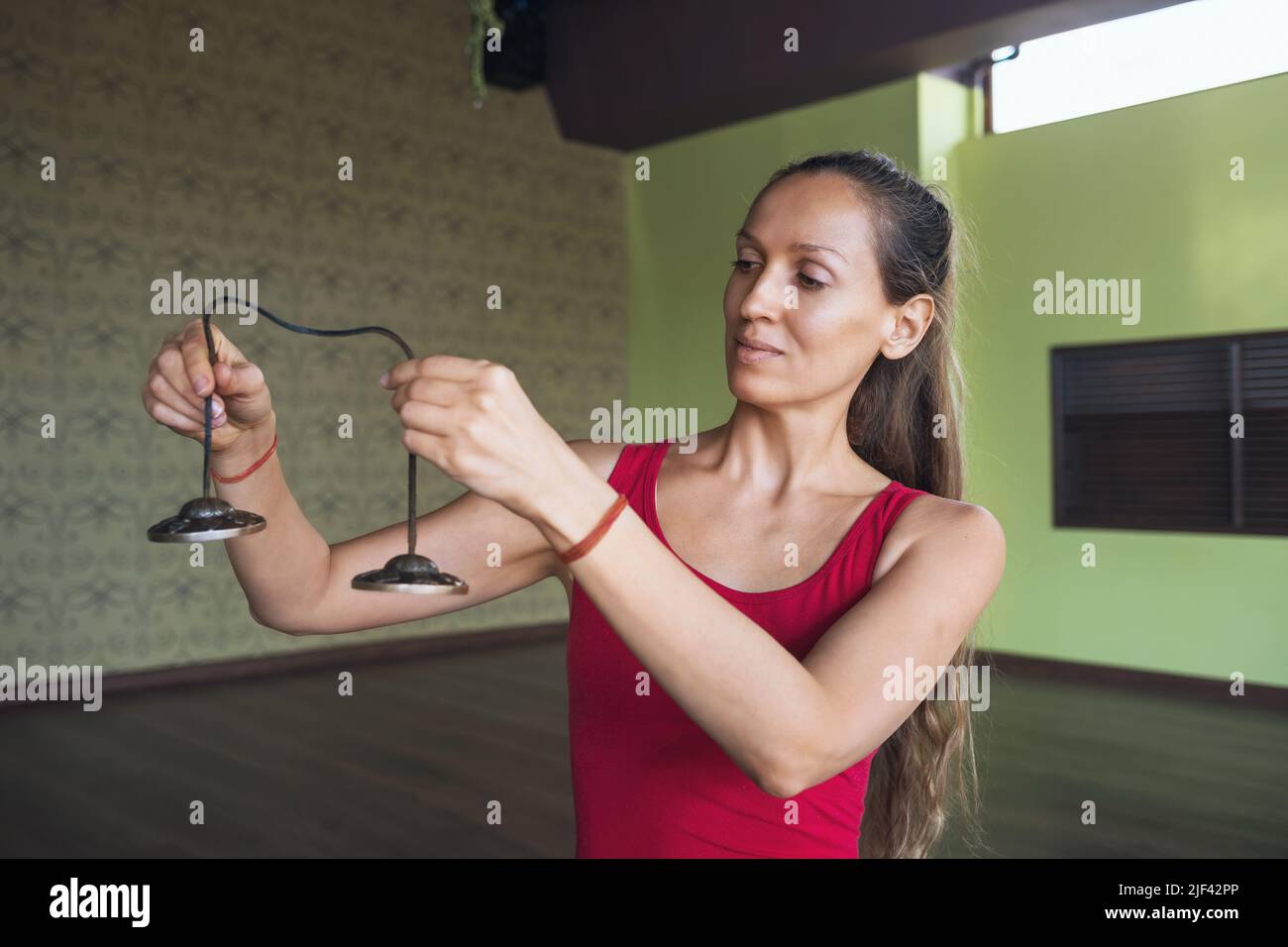 Portrait einer Frau, die Yoga praktiziert und Klangmeditation mit Glocken im Raum macht Stockfoto