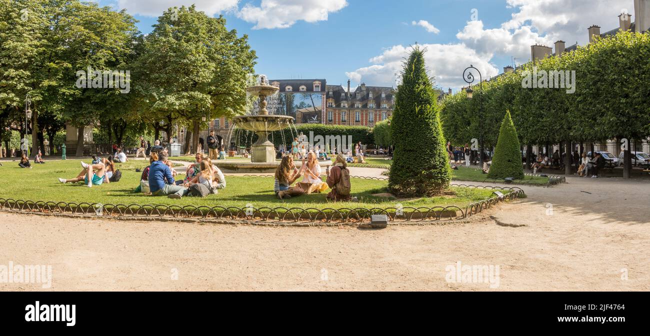 Place des vosges, Paris. Menschen entspannen sich an einem heißen Tag in der Nähe des Brunnens am ältesten Platz von Paris, Frankreich. Stockfoto