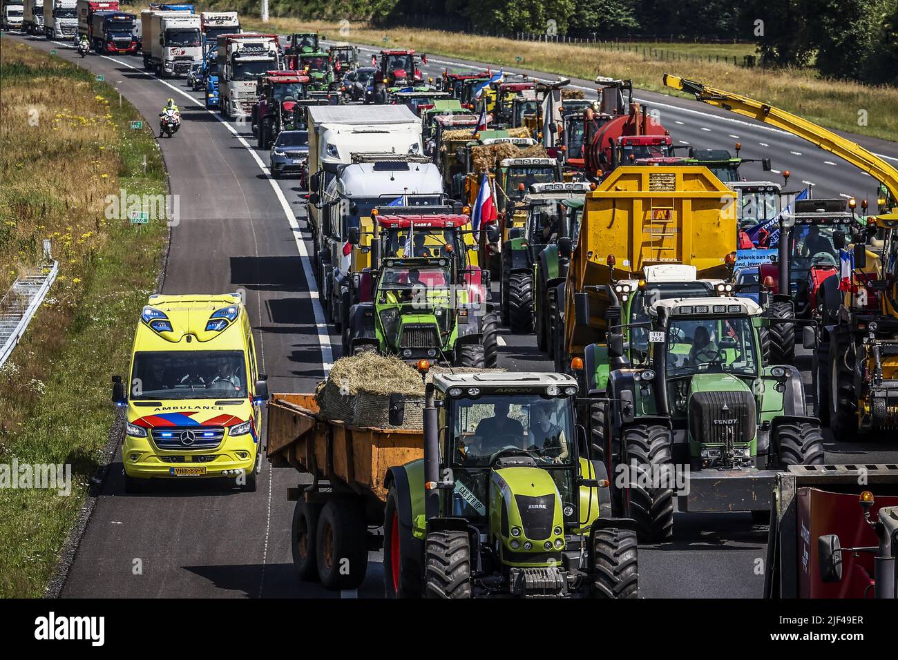 Oldenzaal, Netherlands, 29/06/2022, 2022-06-29 14:37:36 ENTER - ein Krankenwagen fährt über die Notfahrbahn vorbei an Traktoren mit protestierenden Landwirten mit Traktoren unterwegs auf der A1 nahe Enter kämpfen Bauern gegen die Stickstoffpläne des Kabinetts. ANP VINCENT JANNINK niederlande Out - belgien Out Stockfoto