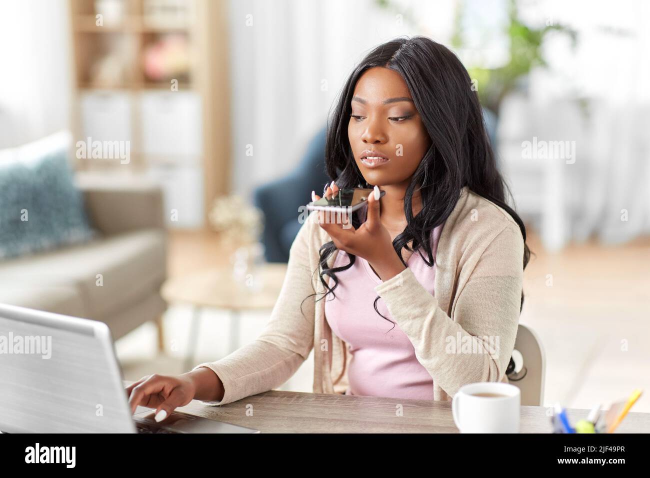 Frau mit Laptop ruft im Heimbüro am Telefon an Stockfoto