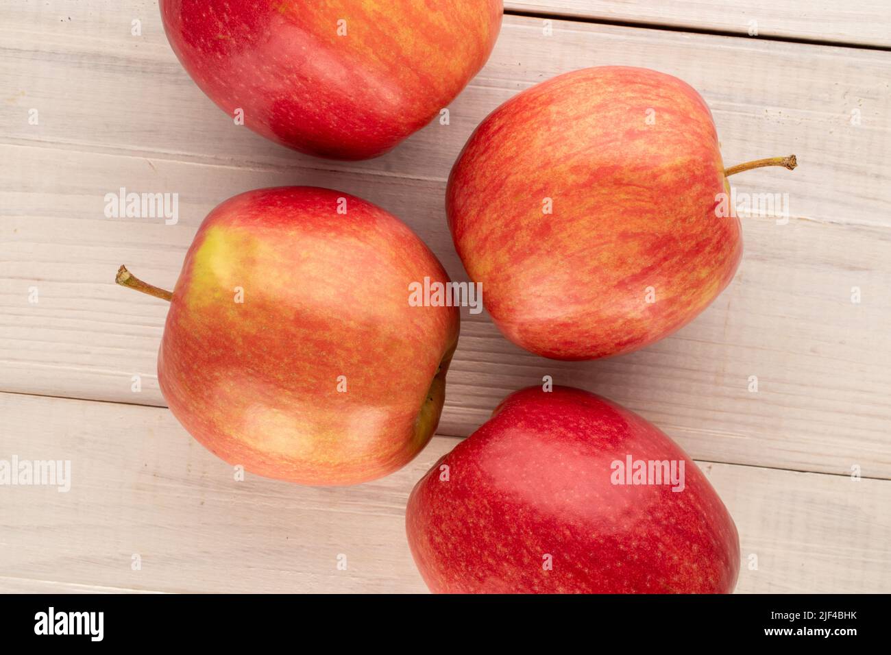 Vier saftige rote Äpfel auf einem Holztisch, Nahaufnahme, Draufsicht. Stockfoto