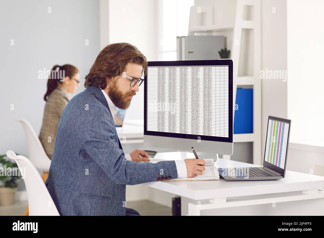 Kaukasischer Mann arbeitet als Buchhalter oder Wirtschaftsprüfer sitzt am Tisch mit Computern im Freiraumbüro Stockfoto