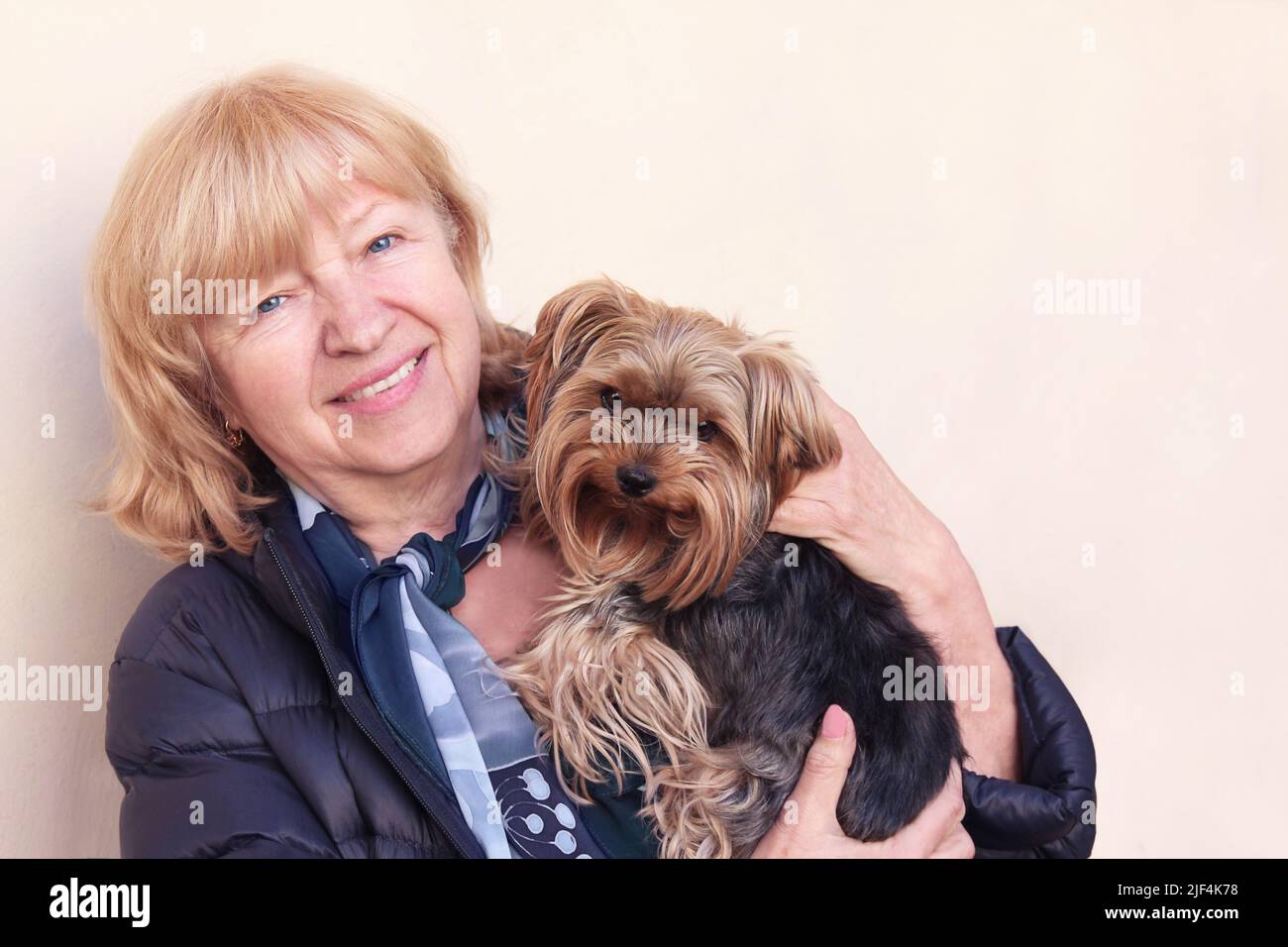Porträt einer schönen, fröhlichen, lächelnden eligen Frau, die ihren kleinen yorkshire Terrier-Hund im Freien umarmt. Stockfoto
