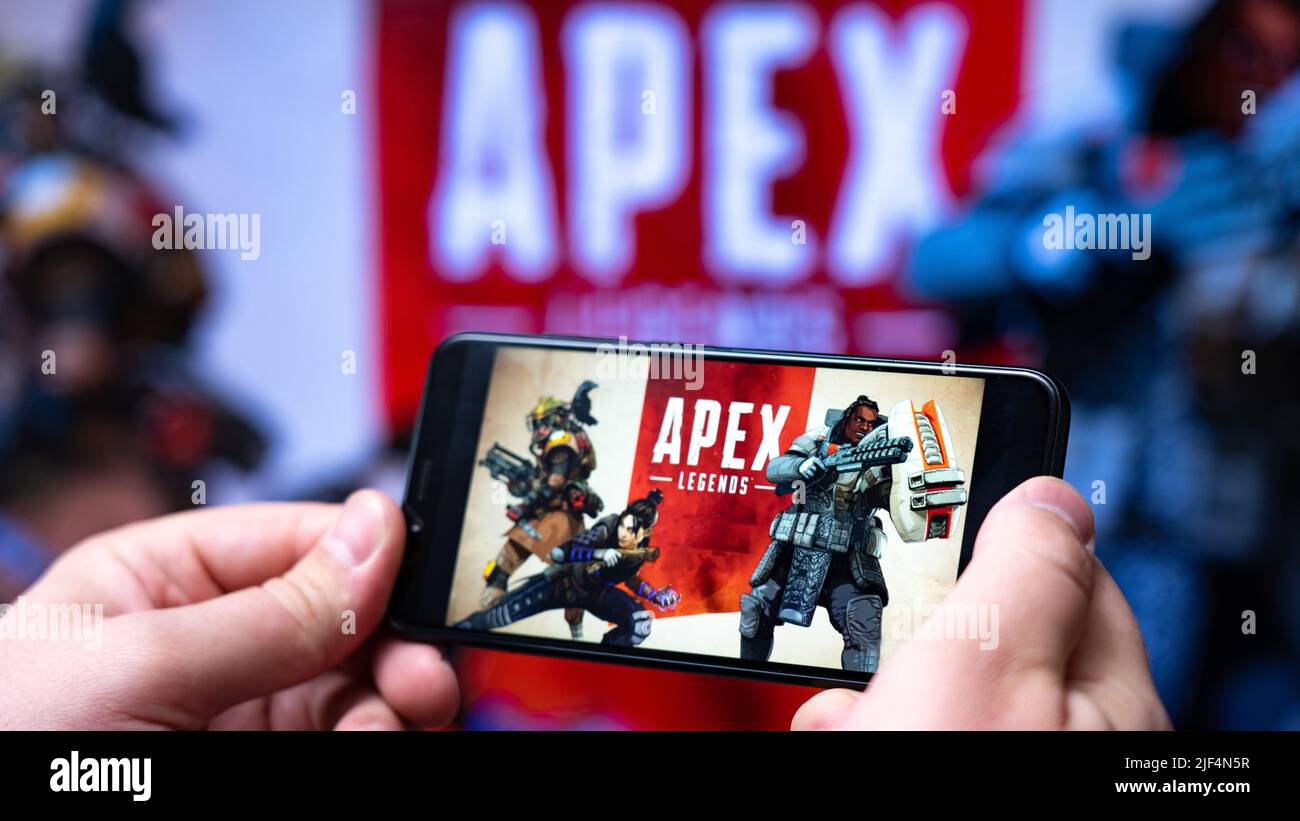 Nova Lima, Brasilien - Juni 2022: Hände halten ein Smartphone mit Apex Legends Mobile vor einem großen Bildschirm. Stockfoto