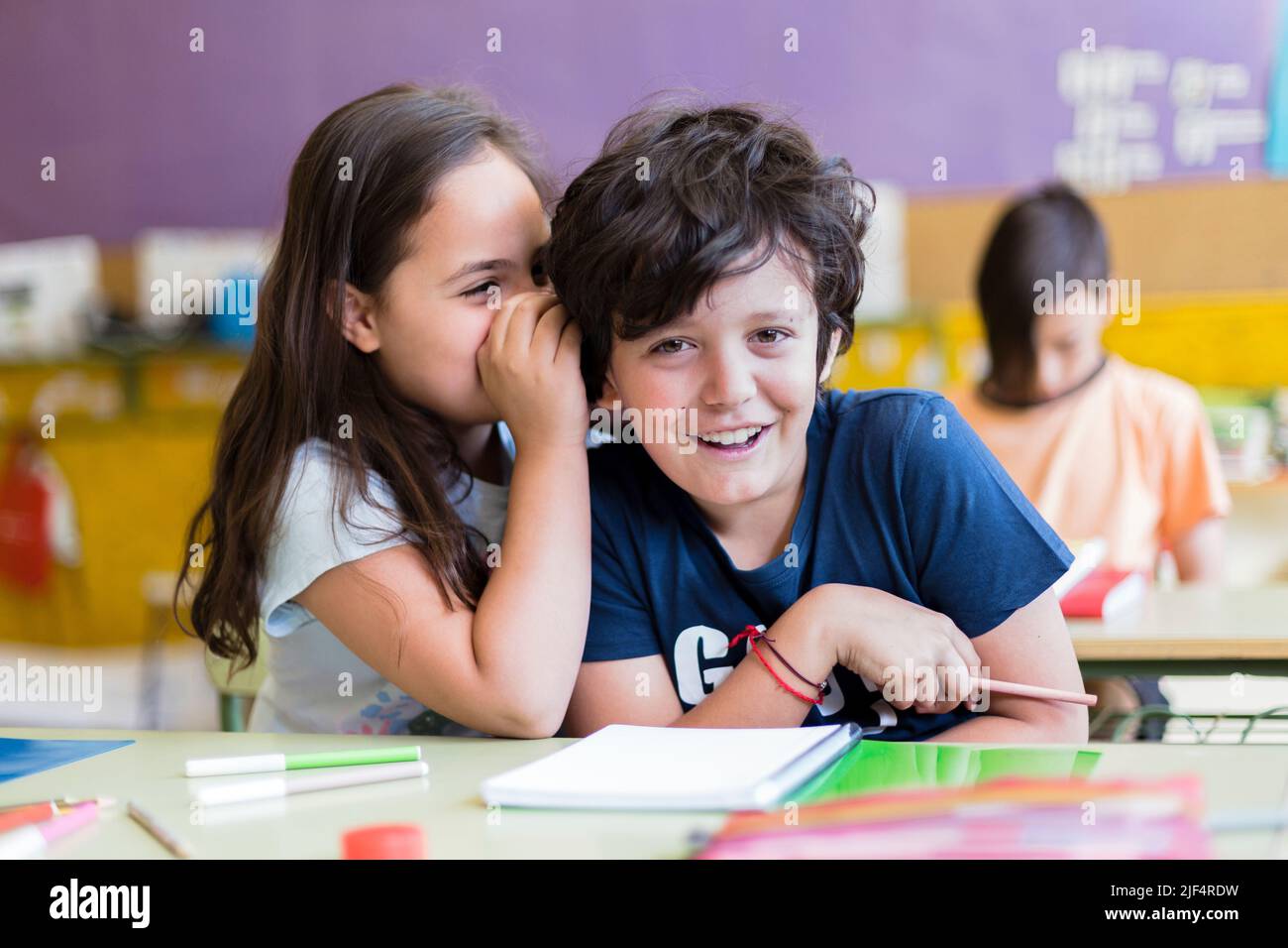 Zwei lustige kaukasische Kinder unterhalten sich im Unterricht miteinander. Grundschulbildung. Zurück zum Schulkonzept. Stockfoto