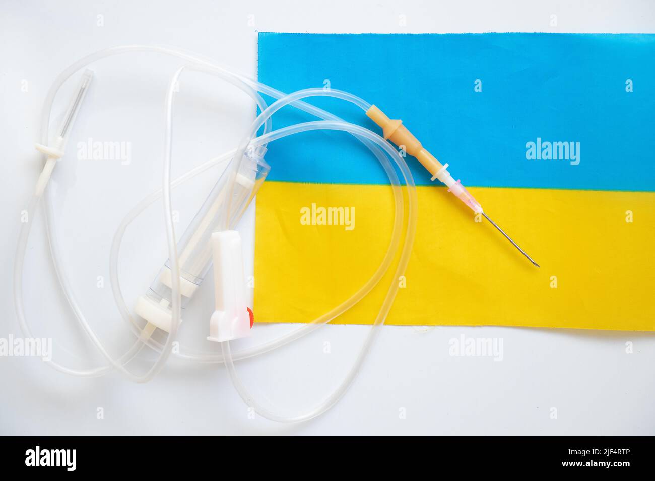 Die Flagge der Ukraine und ein medizinischer Tropfer liegen auf weißem Hintergrund, Medizin in der Ukraine, ein Tropfer und eine Nadel Stockfoto