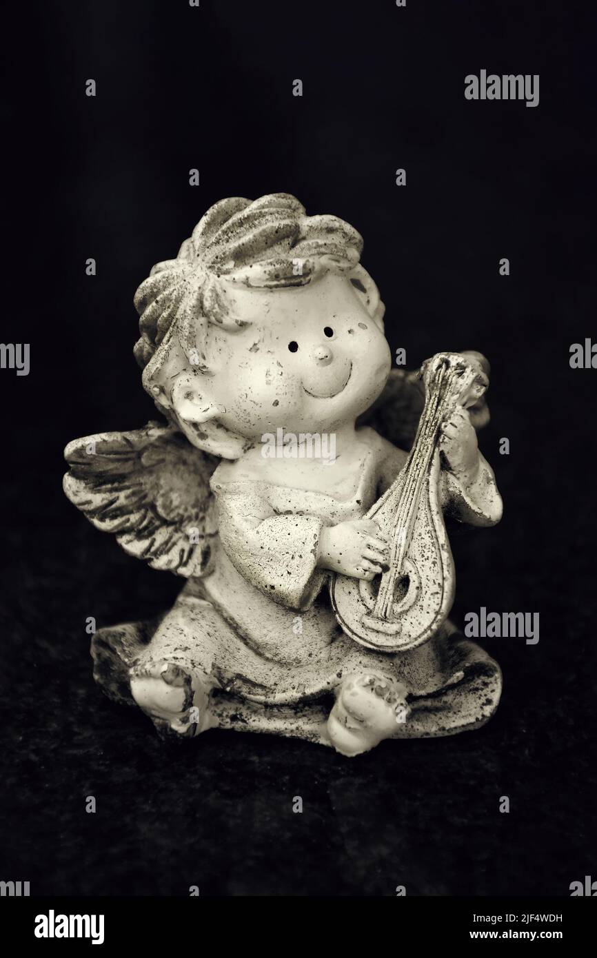 Engel mit Mandoline auf schwarzem Hintergrund Stockfoto