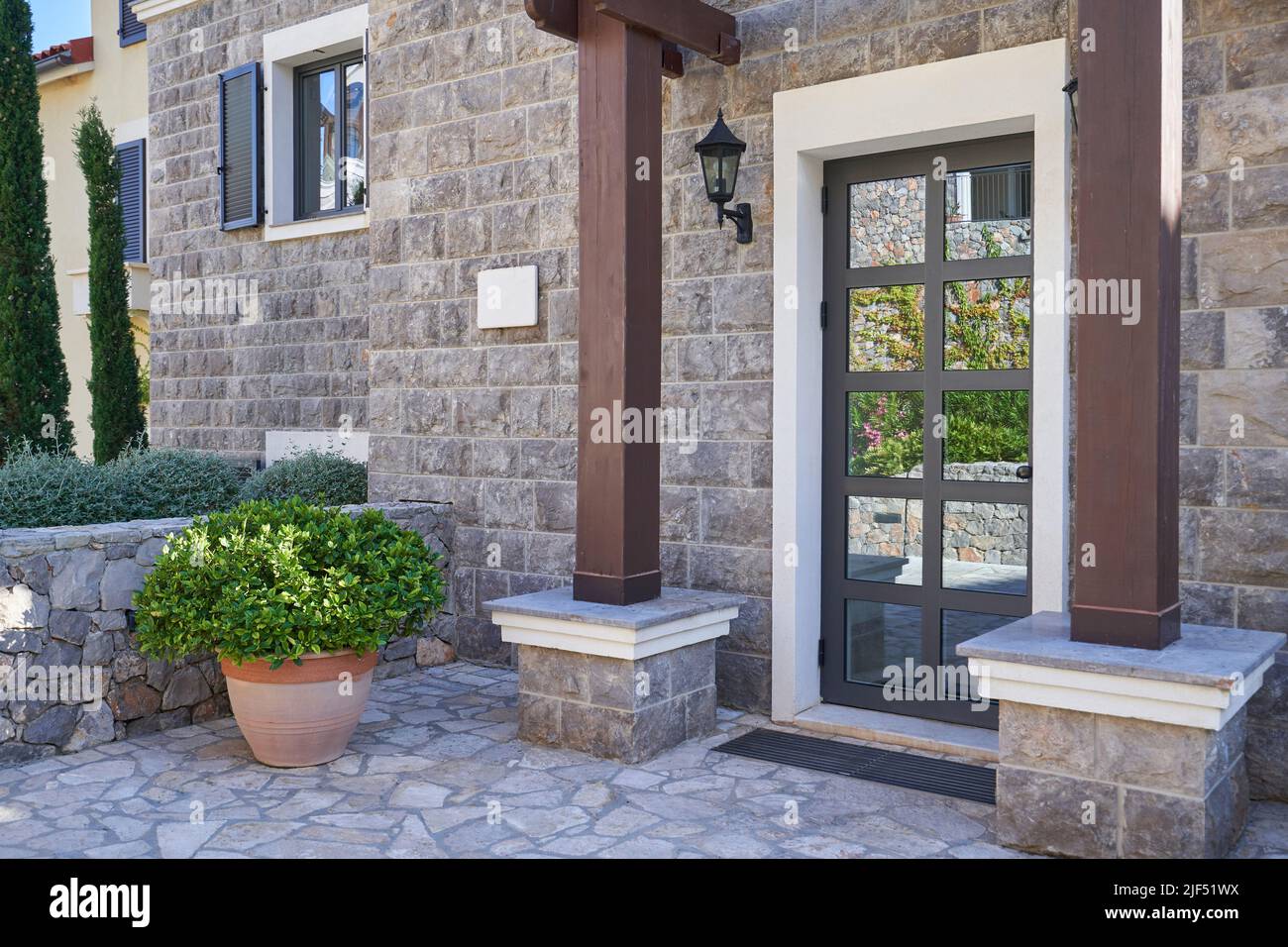 Eingang zum Haus mit Glastür und Steinmauer. Stockfoto