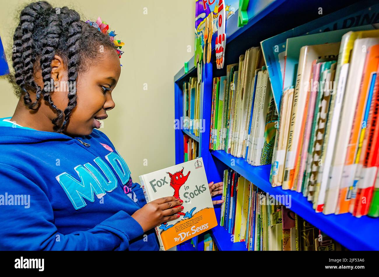 Ein afroamerikanisches Mädchen wählt während eines Nachschulprogramms am 28. Februar 2013 in Columbus, Mississippi, ein Buch von Dr. Seuss aus einem Bücherregal aus. Stockfoto