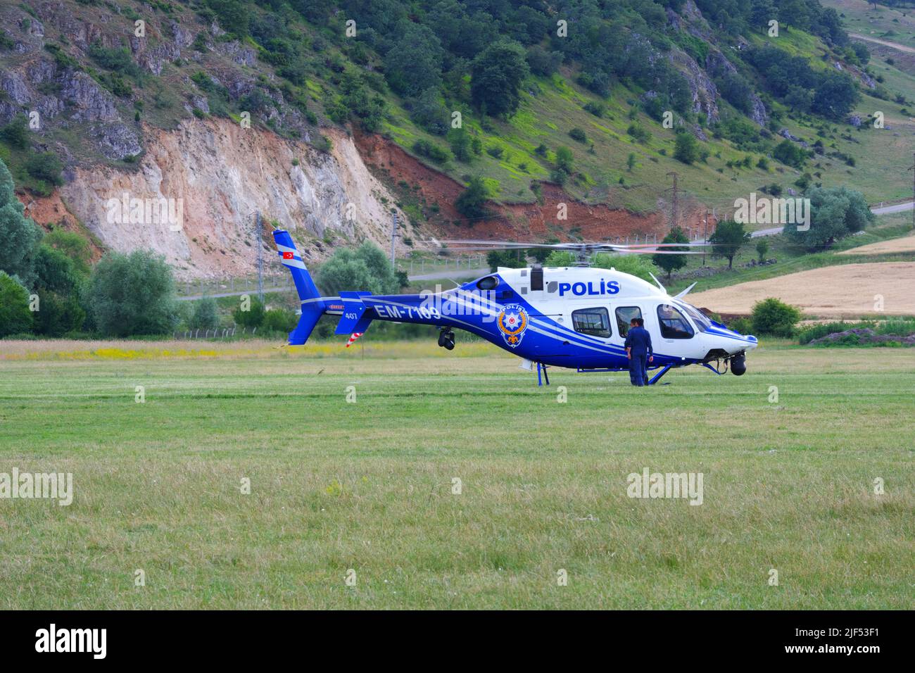 Der türkische Polizeihubschrauber landete, um Mitarbeiter vom Grasland vor Hügeln zu holen Stockfoto