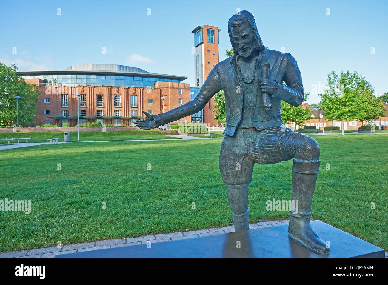 Statue von William Shakespeare mit ausgestrecktem Arm in den Bancroft Gardens Stratford-upon-Avon, dahinter das Royal Shakespeare Theater Stockfoto