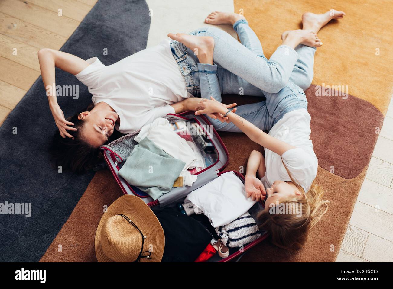 Mutter und Tochter träumen von einer Reise, liegen auf dem Boden und packen einen Koffer. Stockfoto
