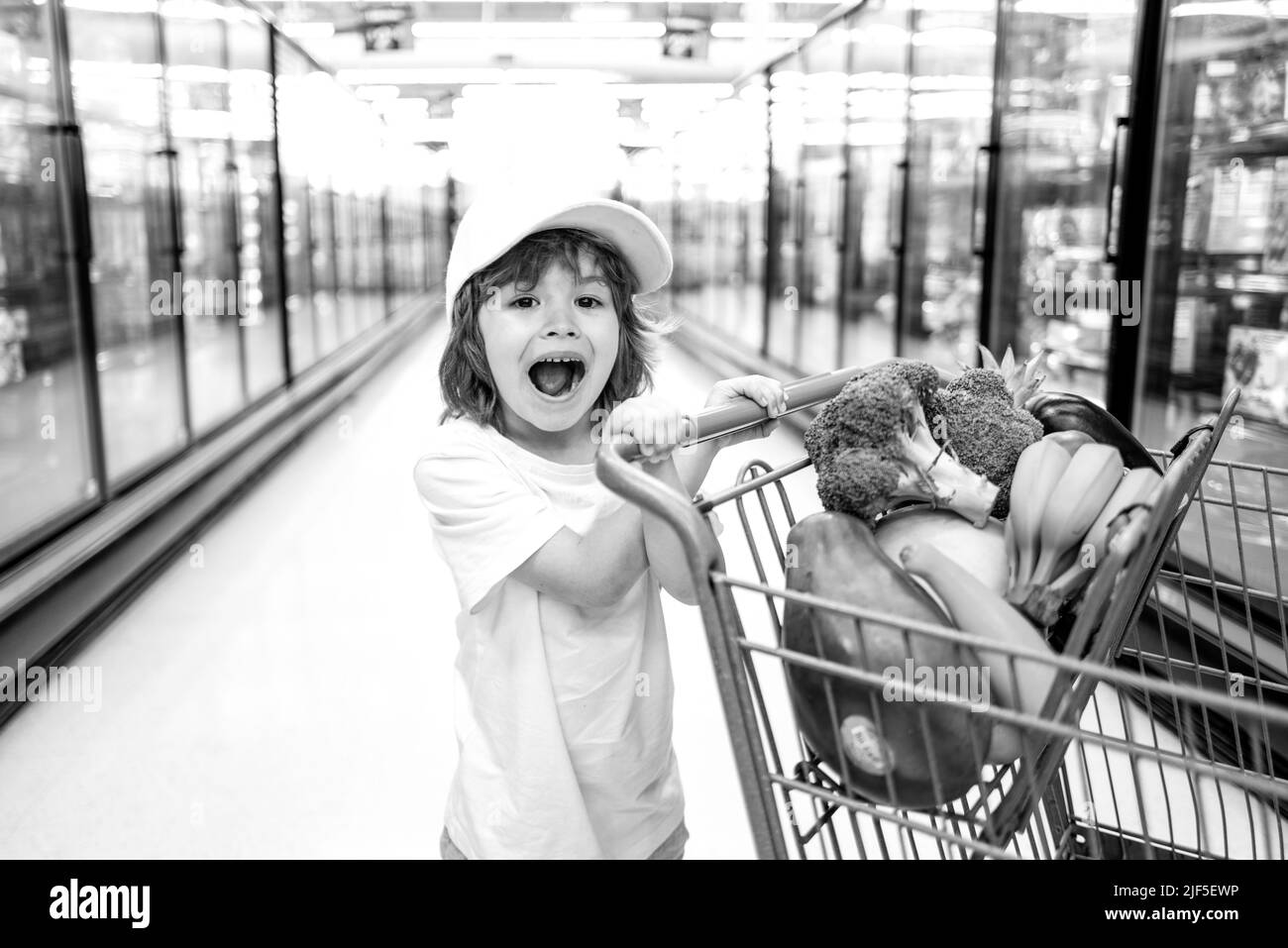 Kleinkind Junge mit Einkaufstasche im Supermarkt. Kinder einkaufen im Supermarkt. Supermarkt, Einkaufen mit Kind. Stockfoto