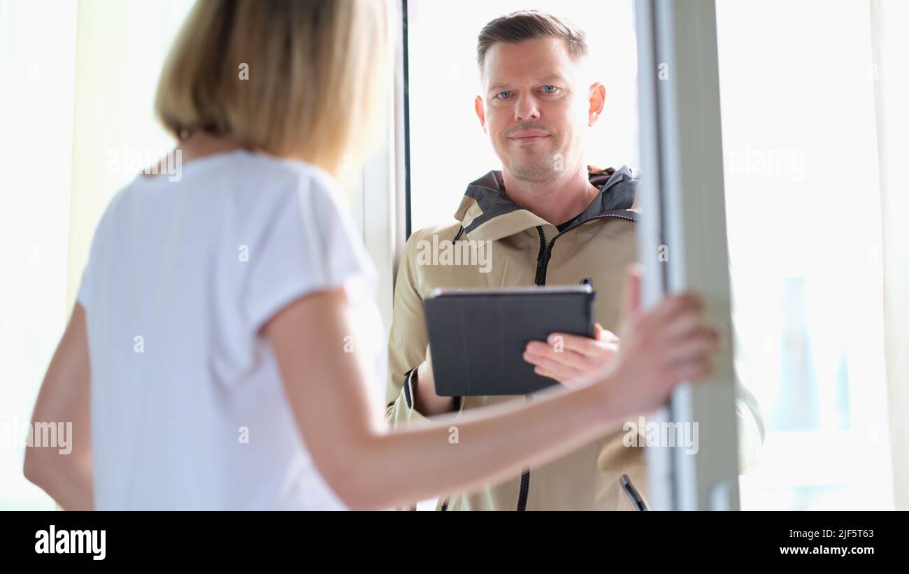 Der männliche Kurier verwendet eine Anwendung auf dem Tablet, um die Zustellung des Pakets vor der Haustür zu bestätigen Stockfoto