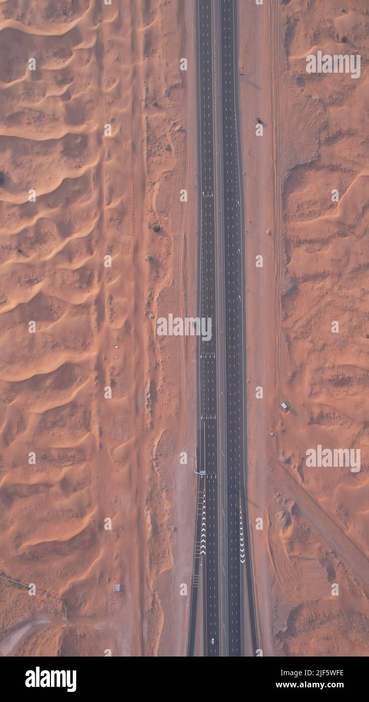 Aus der Vogelperspektive auf Sanddünen und eine Autobahn in einer Wüste von Sharjah, VAE, Naher Osten Stockfoto