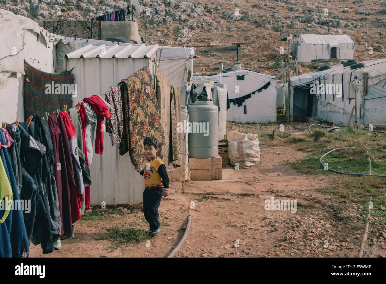 Junge geht ruhig zu seinem Zelt. An einem Morgen in einem Flüchtlingslager im Bekaa-Tal leben rund 20 Familien. Einige Familien warten seit fünf Jahren darauf, an einen anderen Ort zu gehen. Selbst wenn die Situation ihnen eine Rückkehr nach Syrien ermöglichen würde, sind die meisten von ihnen nur canít. Die im Libanon geborenen Kinder haben keinen syrischen Pass, sind aber im Land registriert. Deshalb bleiben auch die Eltern auf dem Land. Viele Eltern haben auch ihre Aufenthaltserlaubnis abgelaufen und können es sich nicht leisten, eine neue auszustellen, da viele von zwei bis drei Dollar pro Tag leben. Stockfoto