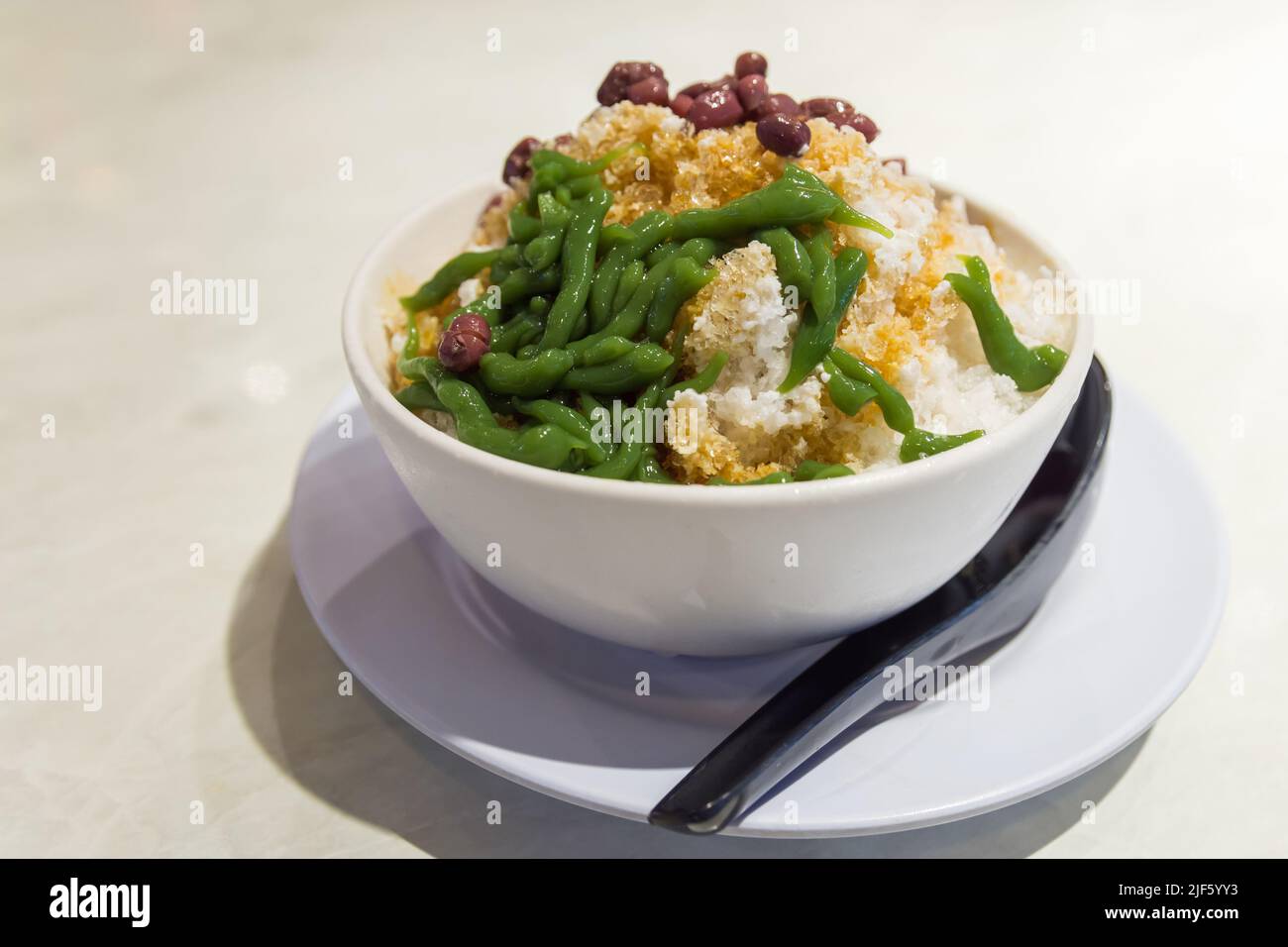 Nahaufnahme des Cendol-Dessert mit gula Melaka-Sirup. Cendol wird aus zerkleinerten Eiswürfeln, Gelee, Kokosmilch und roten Bohnen hergestellt. Stockfoto