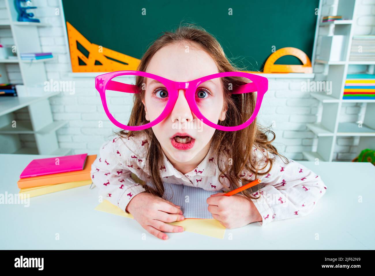 Lustige Geek überrascht Kind Schulmädchen mit Spaß Brille im Klassenzimmer. Zurück zur Schule. Stockfoto