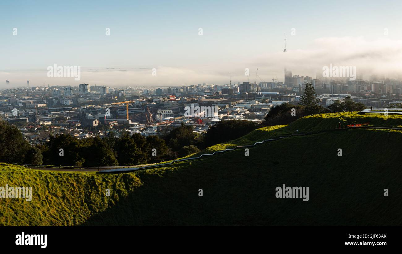 Blick vom Gipfel des Mount Eden mit Nebel, der über den Sky Tower und die Stadt Auckland driftet Stockfoto