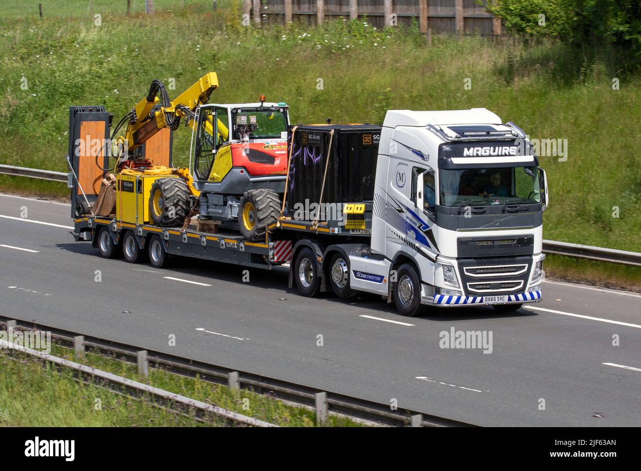 MAGUIRE Industrieverkehr. Volvo 1277cc Traktor Unit Towing LIDER Anhänger Tieflader mit M540 Kelly Earthmoving Ausrüstung auf der Autobahn M61 UK Stockfoto