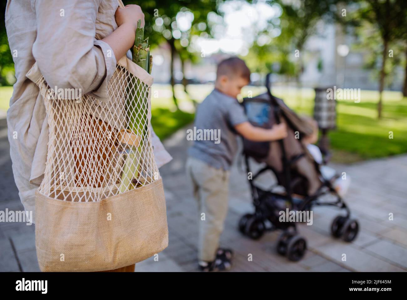 Junge Mutter mit Null-Abfall-Einkaufstasche mit ihren Kindern und Spaziergang in der Stadt Straße, Nahaufnahme Stockfoto