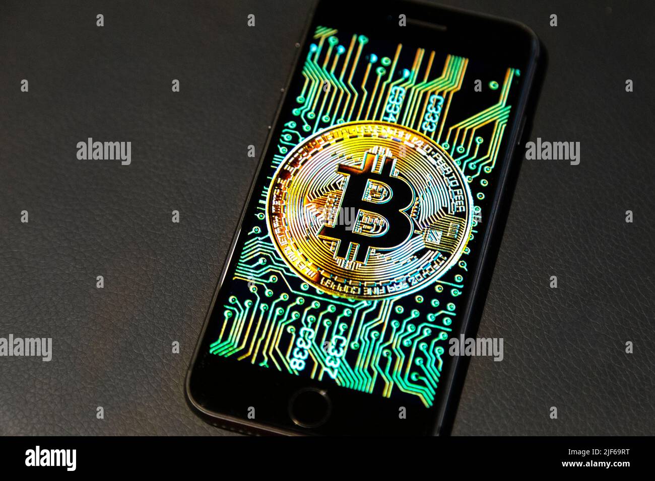 Bitcoin-Logo auf einem Telefonbildschirm vor einem Lederhintergrund Stockfoto