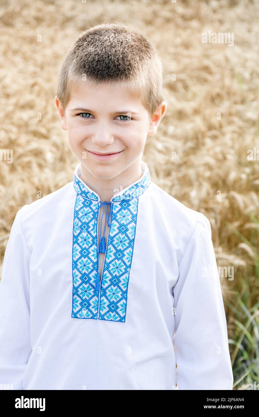 Soft Focus Porträt des Schuljungen in traditionellen bestickten ukrainischen Hemd auf dem Hintergrund des Weizenfeldes an sonnigen Tag. Kind lächelt aufrichtig. Unabhängigkeitstag, Verfassung der Ukraine. Stockfoto