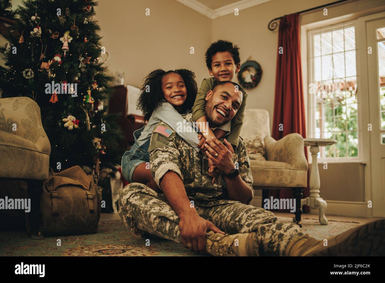 Glückliche Militärfamilie lächelt freudig, während sie Weihnachten zusammen verbringt. Fröhlicher Militärvater, der zu Weihnachten wieder mit seinen Kindern zusammenkommt. Soldat spen Stockfoto