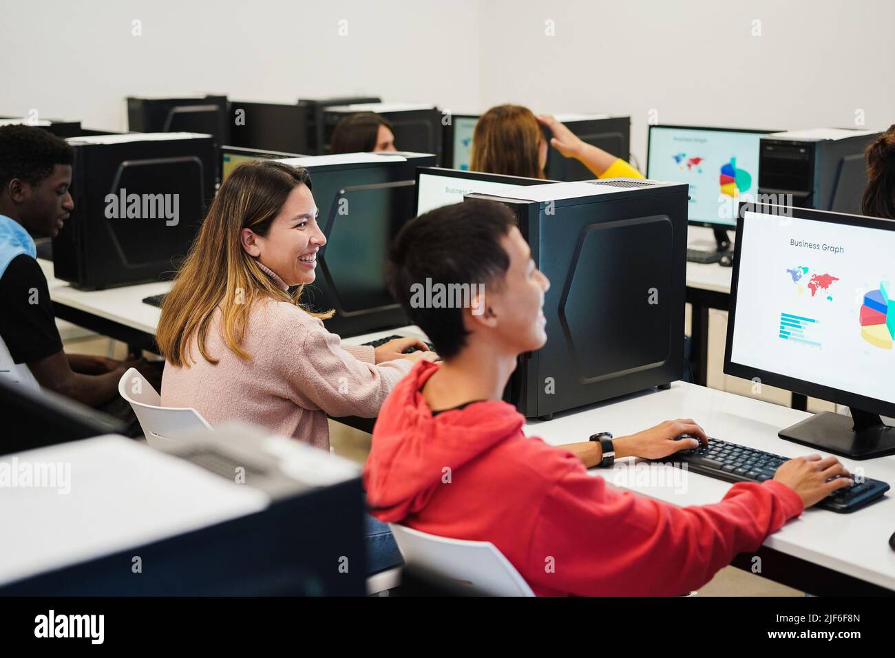 Junge Studenten mit Computern in der Technologie-Klasse im Schulzimmer - Fokus auf Mitte Mädchen Gesicht Stockfoto