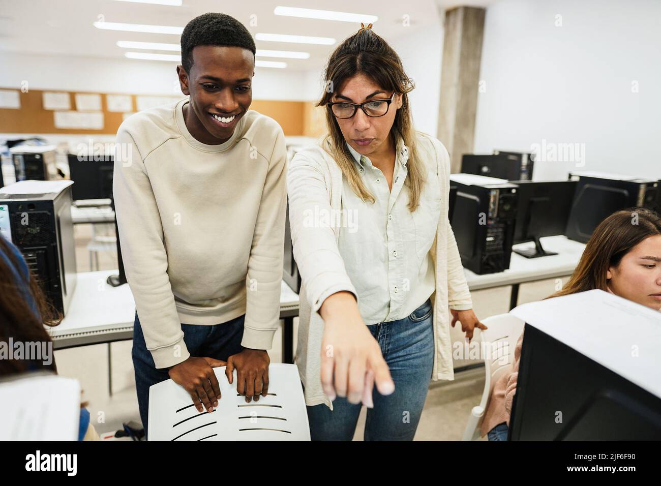 Lehrer, der mit Schülern im Computerraum arbeitet - Fokus auf das Gesicht der Frau Stockfoto